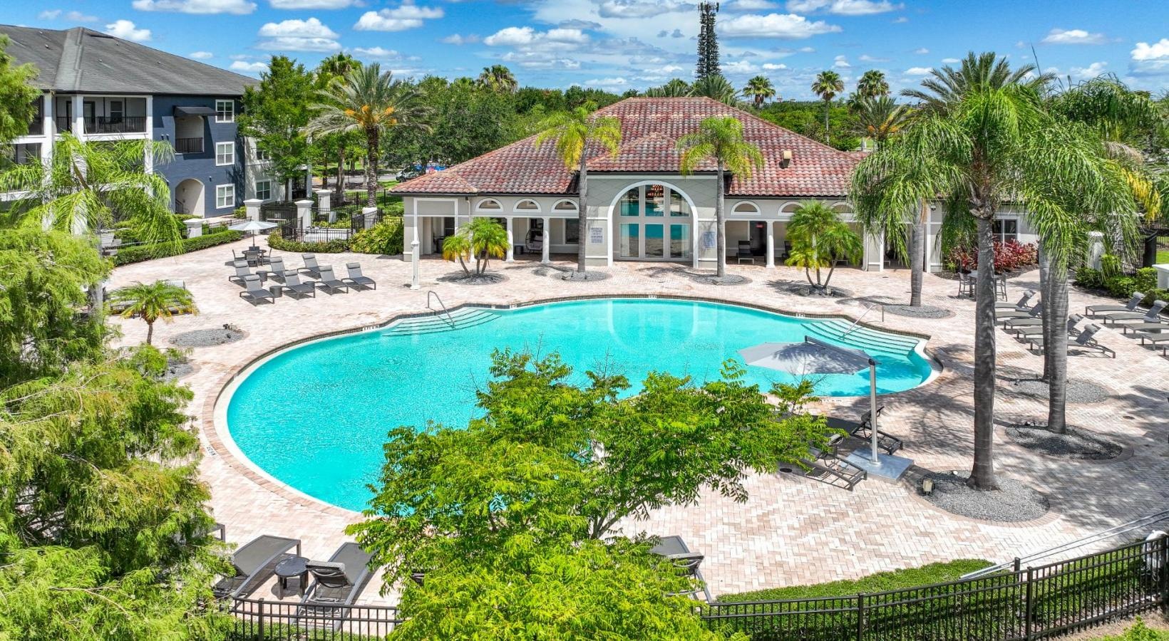 Relax and unwind poolside a pool surrounded by trees and a building