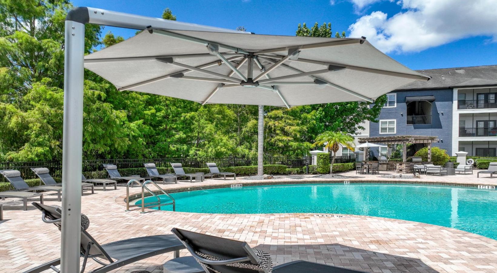 Resort-style swimming pool a pool with chairs and a covered area next to it