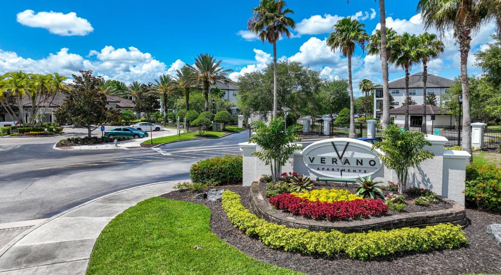 Settle into comfort at Verano an entrance with palm trees and a sign