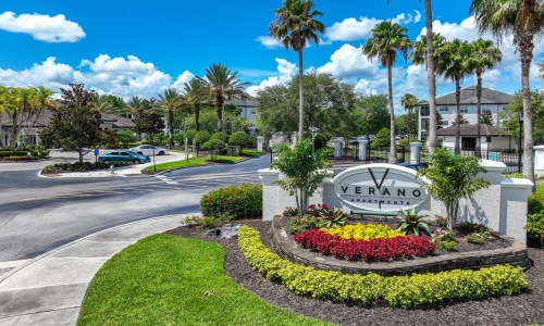 Settle into comfort at Verano an entrance with palm trees and a sign