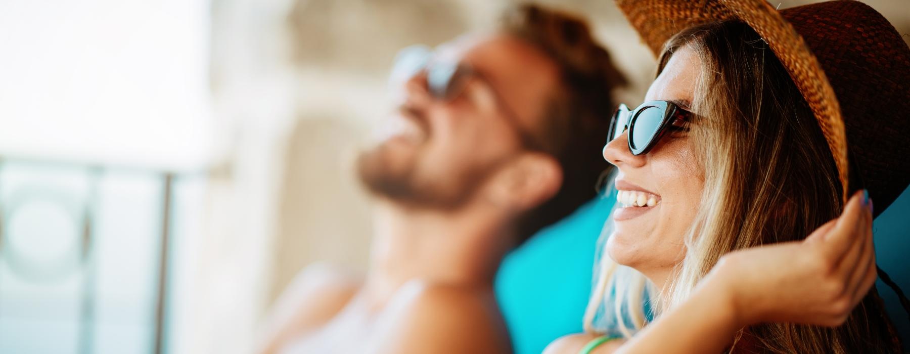 a man and woman looking at a book and sun bathing