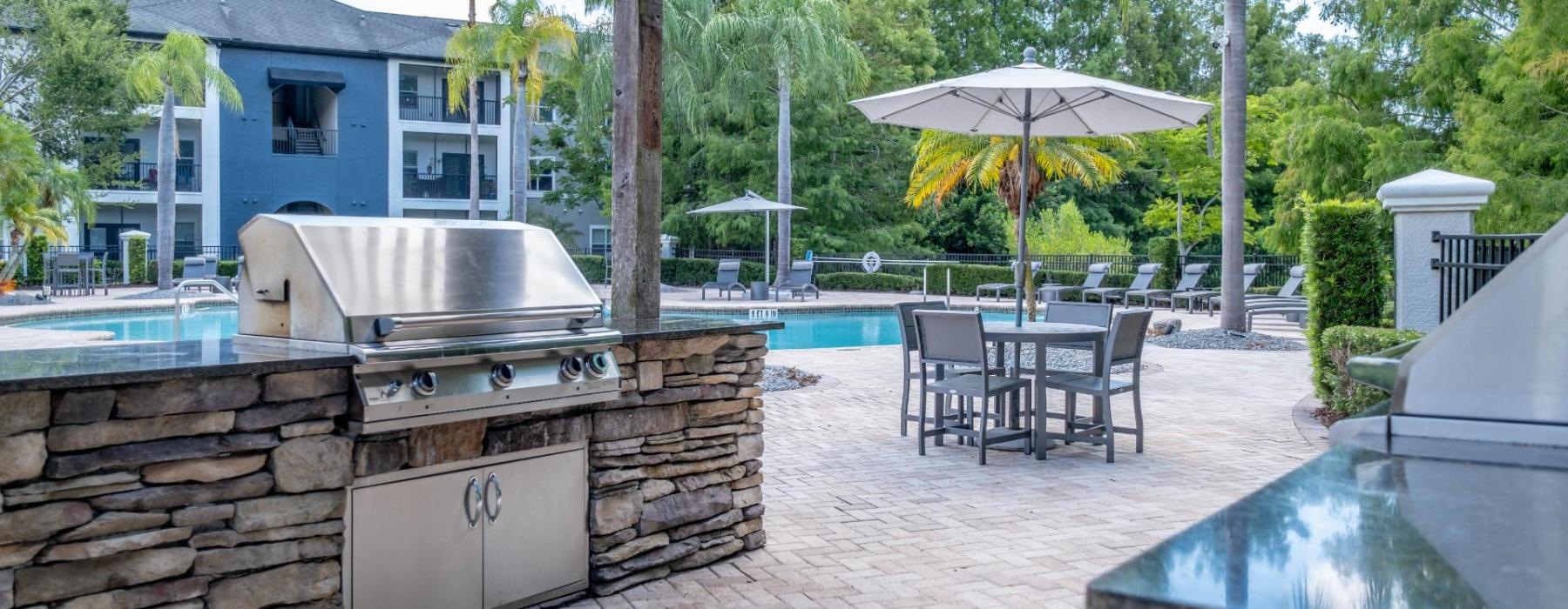 a patio with a grill and umbrella